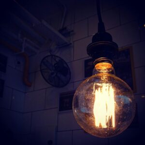 A glowing vintage Edison bulb hanging indoors, creating a warm, cozy atmosphere.